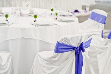 Beautiful wedding set decoration in the restaurant. Chairs with violet ribbons.
